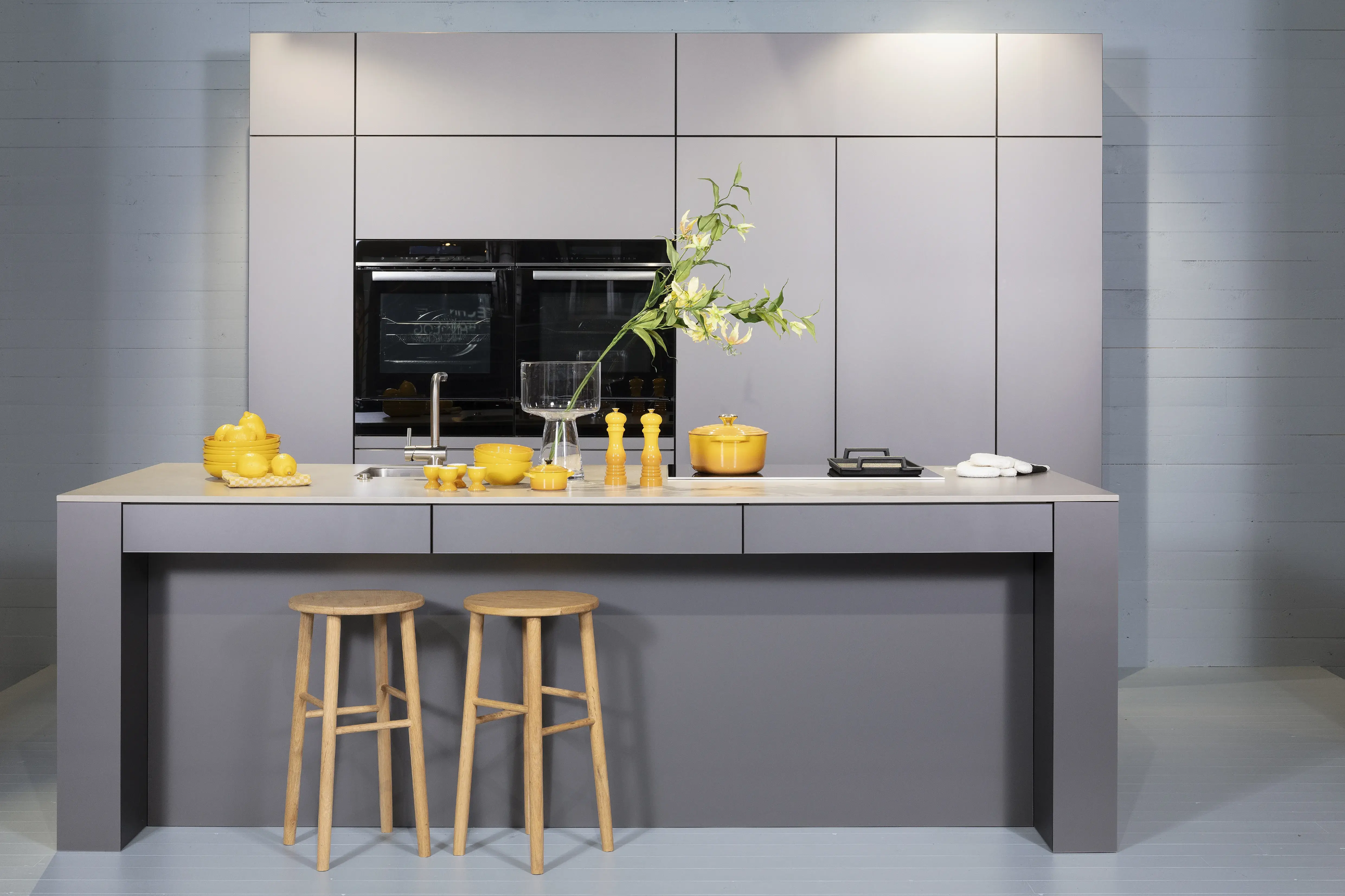 Häcker-Küche in Sandgrau metallic mit Stühlen als frontaler Vollschuss. 