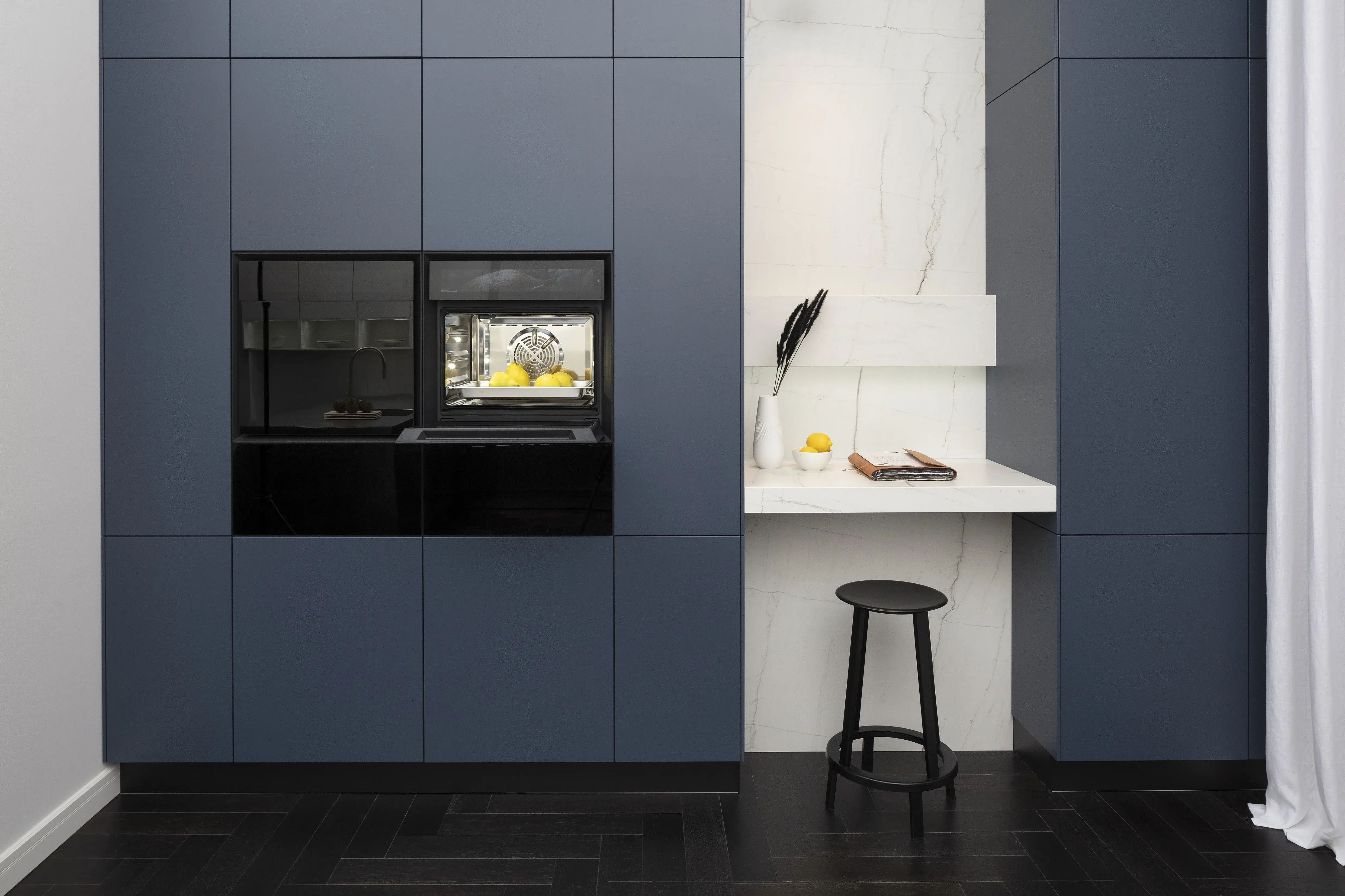 Front: Industriestahl Metalliclack geschliffen AV6000 NCS Mattlack APL: Franke Edelstahl 6 mm Geräte: Bora Spüle Armaturen: Franke  Features: Metallfront, Spülbecken in APL integriert (aus einem Guss), Oberschränke mit Lowboard-Charakter, integrierter Arbeitsplatz, dunkler Korpus mit Aluminium-Abschlussleiste, Wärmeschublade mit Gittereinsatz.