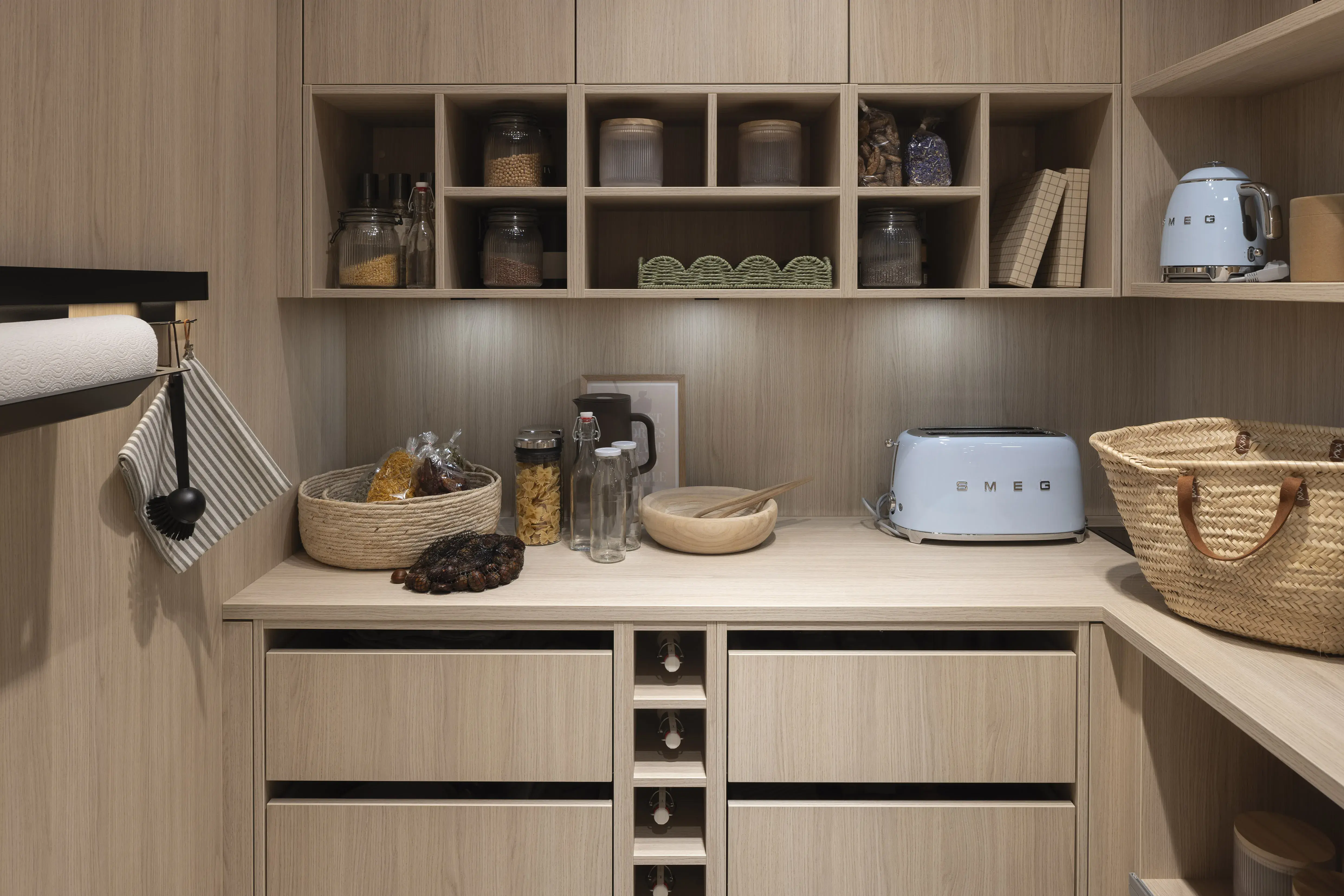 Helle Hauswirtschaftsraum mit Regalen, Vorratsgläsern, Brotkorb und blauem Toaster.