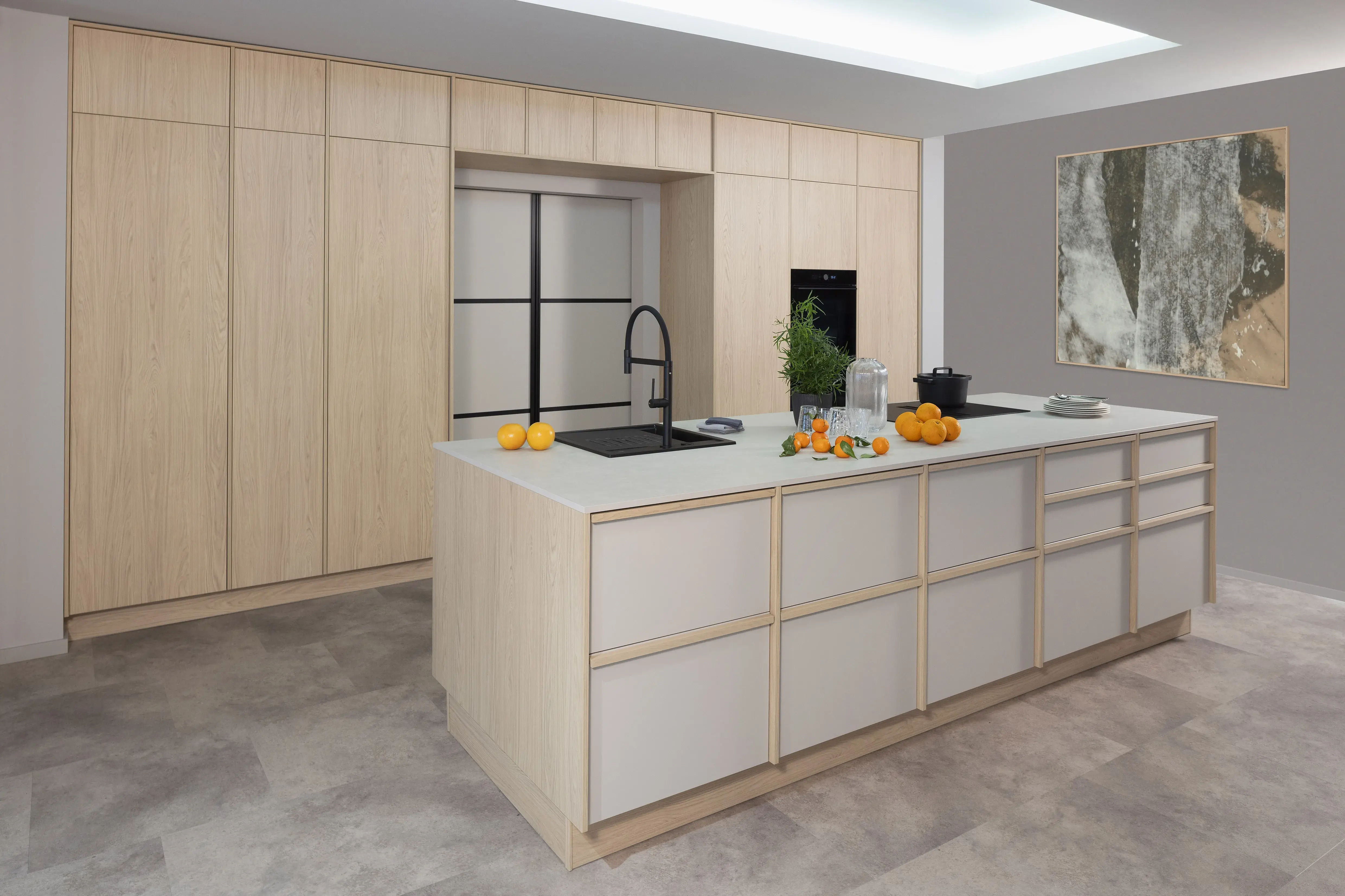 Moderne Küche mit hellem Holz, Kochinsel, Obst und großem Wandbild
